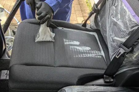 専用機材のリンサーを使用し、セレナのシートに染み込んだ嘔吐汚れを強力吸引洗浄する様子。