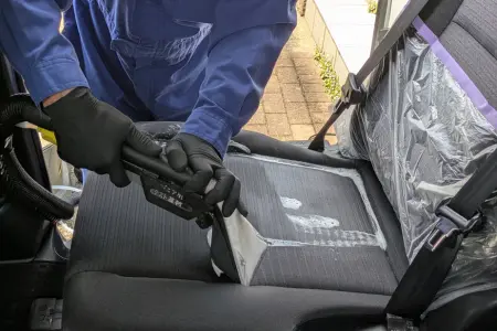 車内の嘔吐トラブル解決のため、シートやフロアの隅々まで清掃を行うプロの工程。